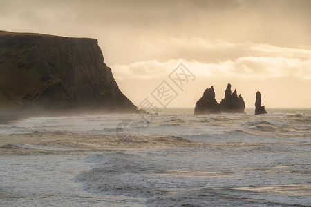 日落时在Dyrholaey的黑火山海滩上形成岩石冰岛日落时在Dyrholaey形成冰岛岩层海景岸线迪尔霍莱图片