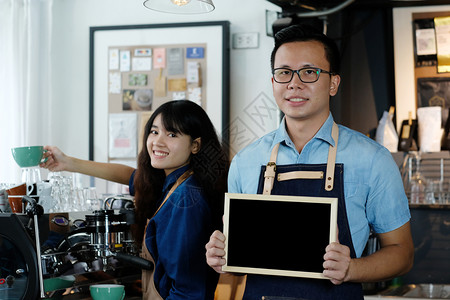 浓咖啡黑板在馆的柜台背景食物和饮料概念上年轻的亚洲小酒巴手拿着面笑脸的空白黑纸板员工图片