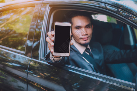 城市电话拥有智能手机和坐在车里的商人微笑图片