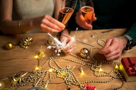 男人幸福的情侣拿着火花和香槟杯新年派对疯狂的笑图片
