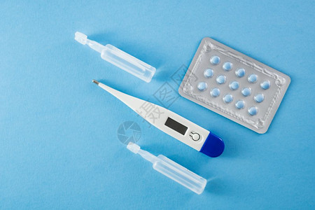 药片安瓿关于蓝背景保健和医疗概念的蓝色药丸薄膜和温度计的一篮子蓝药丸胶囊和温度计药店图片