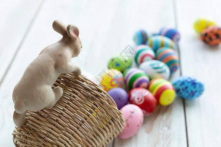 传统的质地复活节假期概念Garden装饰品首在篮子上的兔雕像花彩的复活节鸡蛋在白糊面上带空间的绿色木质背景粉的图片