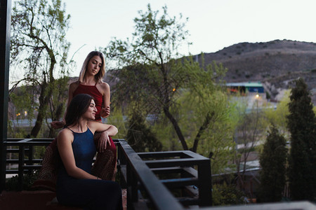 漂亮的两个年轻天主教女青年在阳台上观看日落的光芒白种人友谊图片