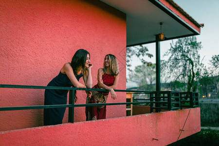 小屋两个年轻的天主教女青年在阳台上观看日落的光芒树木长裙图片