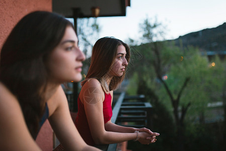 手表红色的两个年轻天主教女青年在阳台上观看日落的光芒黑发图片