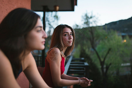 女孩们蓝色的两个年轻天主教女青年在阳台上观看日落的光芒图片