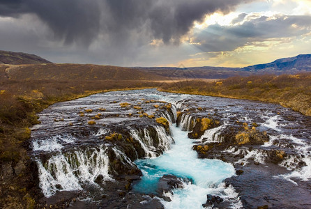 流动夏令Bruarfos冰岛南部的瀑布与色彩多的日落蓝水绿松石图片