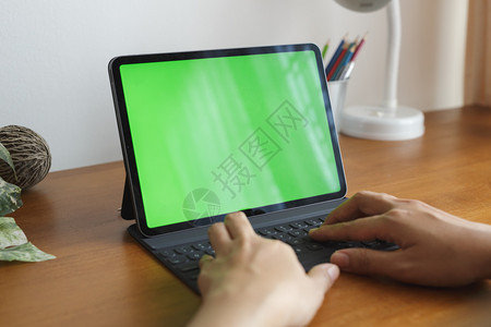 桌面多媒体亚裔女手在使用平板电脑桌上有绿色屏幕子图片