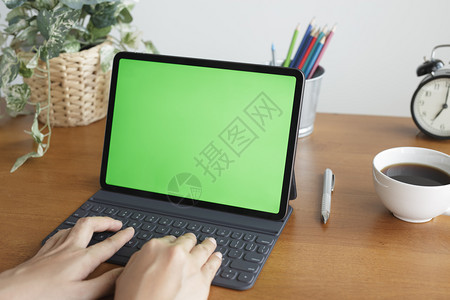 木制的数字笔记本电脑亚裔女手在使用平板电脑桌上有绿色屏幕图片