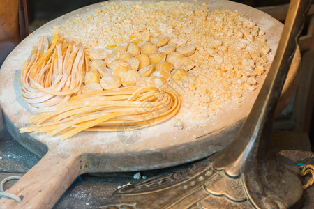 准备好的烹饪木制剪板上的面粉和意大利面生的图片