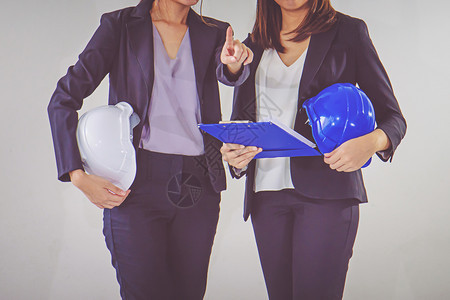 美丽的项目两名女实业工程师头盔手拿着一块石板经理图片