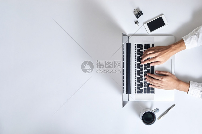 木制的互联网白色一名男子在现代白色办公桌台的手提电脑键盘上打字最高视图图片