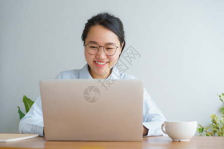 青少年在主办公台做笔记本电脑工作的年轻女微笑在职的图片