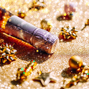 有创造力的魅圣诞或新年配有一瓶玫瑰香槟和金色闪亮背景的花彩装饰喜庆布基和影子的侧观以及庆祝党的创造概念以庆祝圣诞节或新年闪光图片