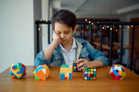 小男孩寻找拼图立方体玩具以进行大脑和逻辑心智训练创造游戏小男孩看谜体年轻的智力为了图片