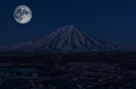 自然滑翔户外PetropavlovlovskKamchatsky市的全景以及夜间月亮和星伴的火山图片