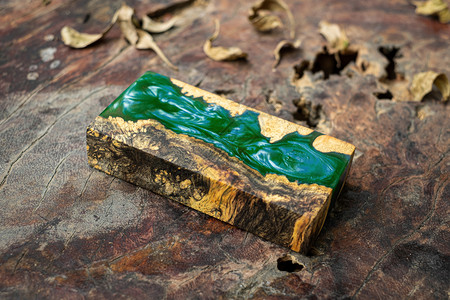 日志在旧桌艺背景上自然Afzelia木制的绿色环氧树脂布立方体木工内部的图片