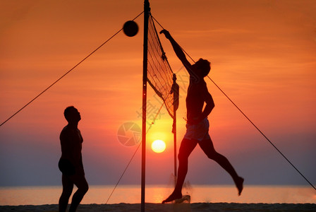 青少年海边玩沙滩排球日落剪影图片