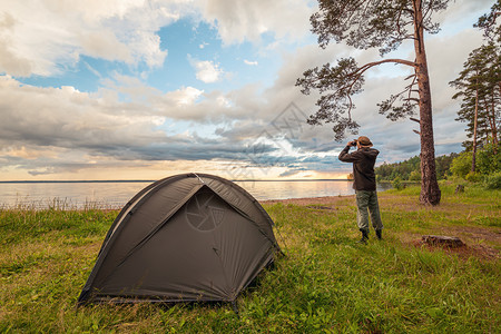 湖岸露营帐篷旅游者通过望远镜观看图片