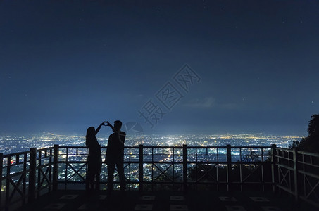男朋友在清迈市之夜双手握表达欢乐的情侣轮光片将一对相爱的情侣Silhouette蜜月情人节图片