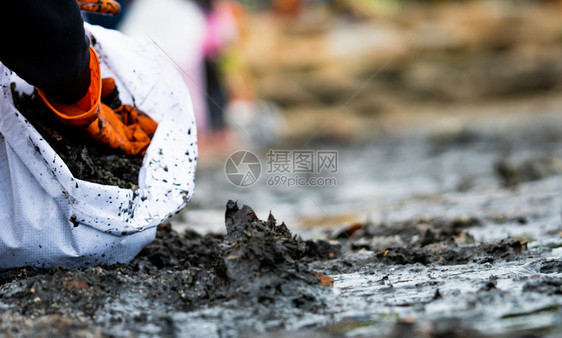 行业志愿者收集垃圾海滩环境污染志愿者清理海滩在模糊背景上打扫清理海滩的沙垃圾堆在海上的油污石渗漏到海上环境的黑色图片