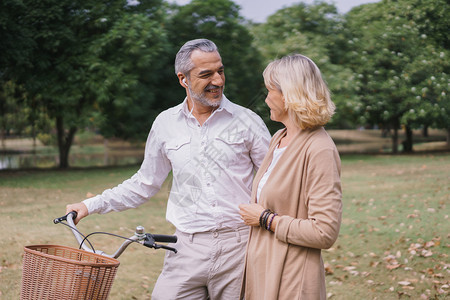老的人们快乐情侣老人在公园里放松骑着自行车散步早上一起聊天健康与放松的概念是健康理夏天图片