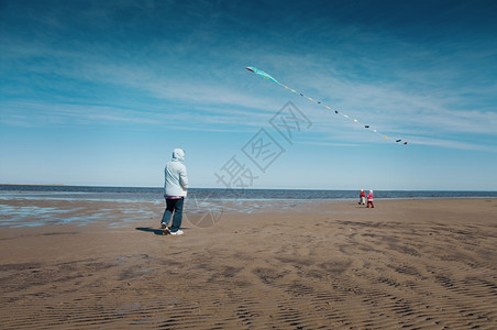 户外快乐的母亲和女儿在沿海上放风筝阳光图片