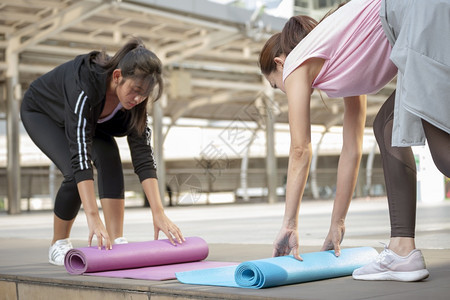 马特力量女双手在瑜伽室外锻炼近亲在上午运动后滚泡沫体操场垫子女在街头城市公园概念上伸展健身运动康生活方式的理念卷图片