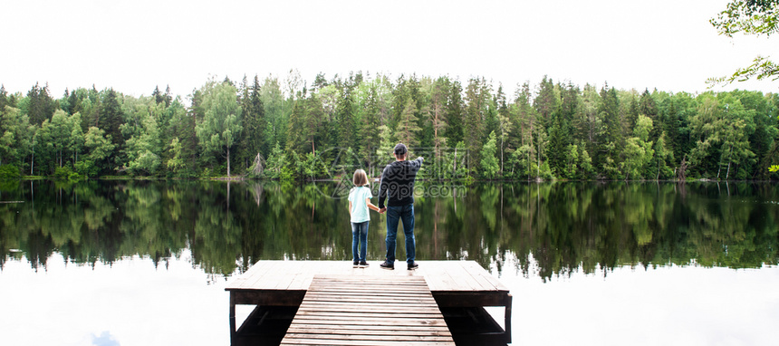 父亲与一个小女儿的父亲正站在美丽的湖码头上父亲正在为他的女儿父和关系概念开辟新的世界而父亲与女儿则站在一个美丽的湖泊码头上天自然图片