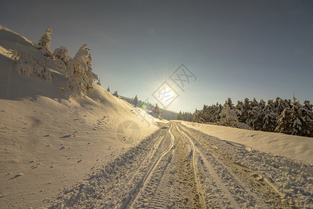 冰冷经过冬季山峰天的路上有太阳雪和汽车足迹的风景冬季乘车旅行的概念户外图片