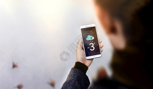 未来展示冬季年轻男子穿着暖身衣漫步使用手机在屏幕顶端查看天气预报时Snow是即将到来的感知寒冷天气雪图片