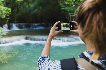 美丽溪流旅游使用智能手机照相以及触碰图片