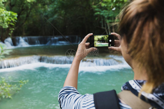 美丽溪流旅游使用智能手机照相以及触碰图片