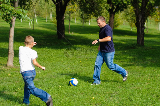 爸爸带着孩子在户外踢球图片