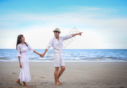 快乐的浪漫情侣人手牵在海滩上散步旅行太阳光图片