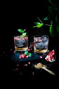 冷冻寒的黑暗两杯夏季饮料配有石榴薄荷和一些黑糖背景图片