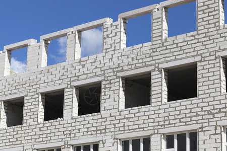 一种建筑物的未完成部分大量白砖和气体硅酸盐块没有玻璃框架的窗户开口在城市建造新的住宅区欧洲砖建筑施工未完成的窗户城市结构体图片