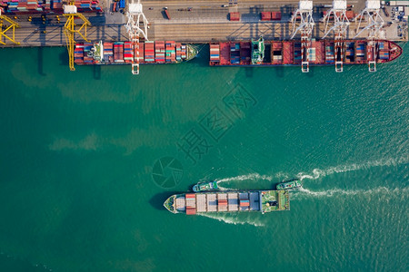 海洋电梯拖船将集装箱通过起重机推向码头以装载集箱用于物流进口出航运或输的空顶端视角航海的图片