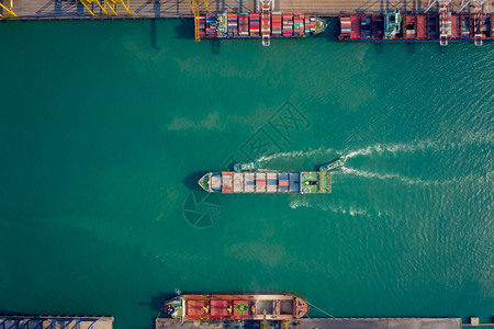 海港拖船将集装箱通过起重机推向码头以装载集箱用于物流进口出航运或输的空顶端视角货图片