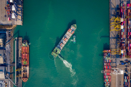 股票盒子海拖船将集装箱通过起重机推向码头以装载集箱用于物流进口出航运或输的空顶端视角图片