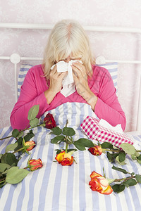 穿着粉红色皮加玛的可怜女人坐在床上带着一堆玫瑰和组织郁闷独自的束图片