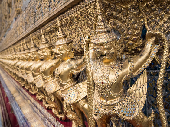 在泰国寺庙的教堂墙周围划一排金雕塑崇拜质地象征图片