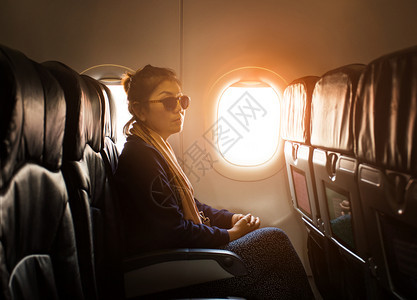 坐着在飞机窗口旁边的孤独亚洲单身妇女用于旅行主题假期活动图片