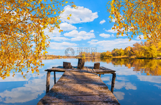秋天在平静的河边Wooden钓鱼码头在河边的Wooden码头放松风景优美橙图片