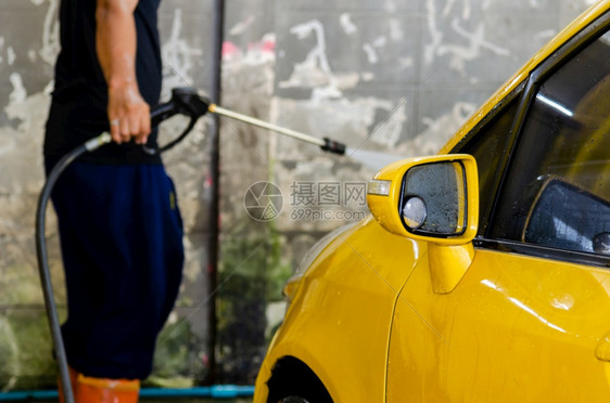 男人喷嘴工具有高压洗车水的男子在CarCarCare汽车正在洗图片