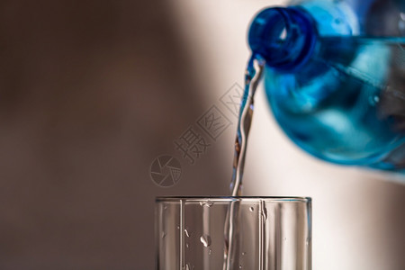 气泡将蓝塑料瓶的水从色塑料瓶浸入底模糊的玻璃杯中选择焦点浅度DF和复制空间满杯的口渴图片