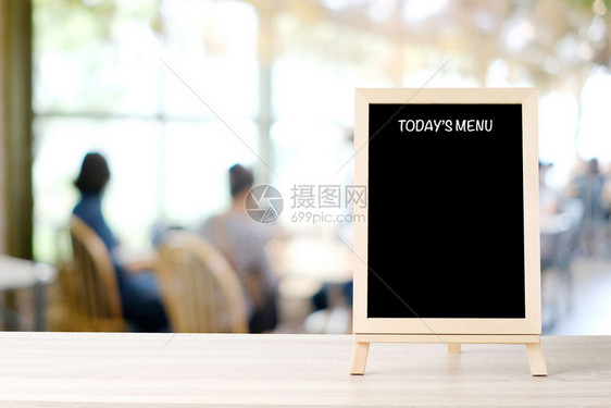 今日股菜单黑板招牌在模糊咖啡店餐馆的桌上有人们背景白黑纸板模拟背景食物和饮料背景概念布兰克粉笔板模拟背景食物和饮料背景概念内部的图片