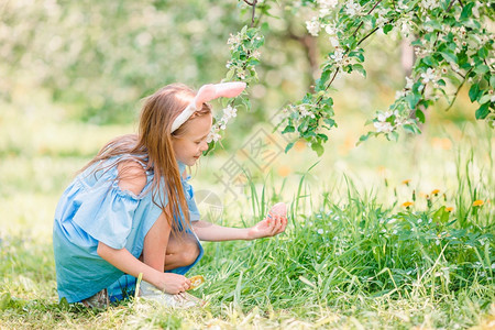 微笑花的季节可爱小女孩在盛开的苹果树花园寻找复活节鸡蛋可爱的小女孩在美丽的春天盛开苹果花园图片