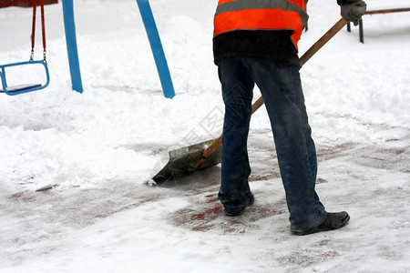 白色的冬季在游乐场除雪一个人拿着铲子从铁轨上扫雪后部户外图片
