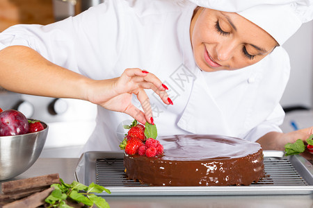 厨房的糕点师装饰巧克力蛋糕抹刀准备帽子图片